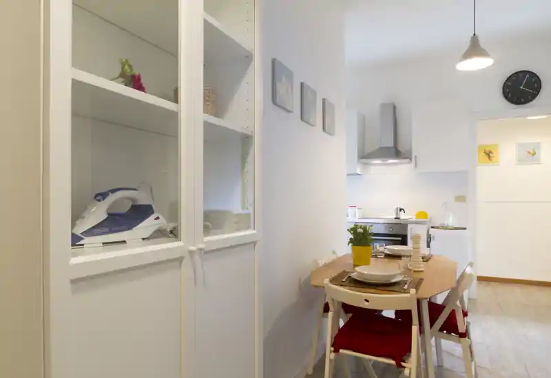 Cocina moderna y compacta con área de comedor pequeña: mesa de madera para cuatro, muebles blancos y campana inox, espacio luminoso y ordenado.