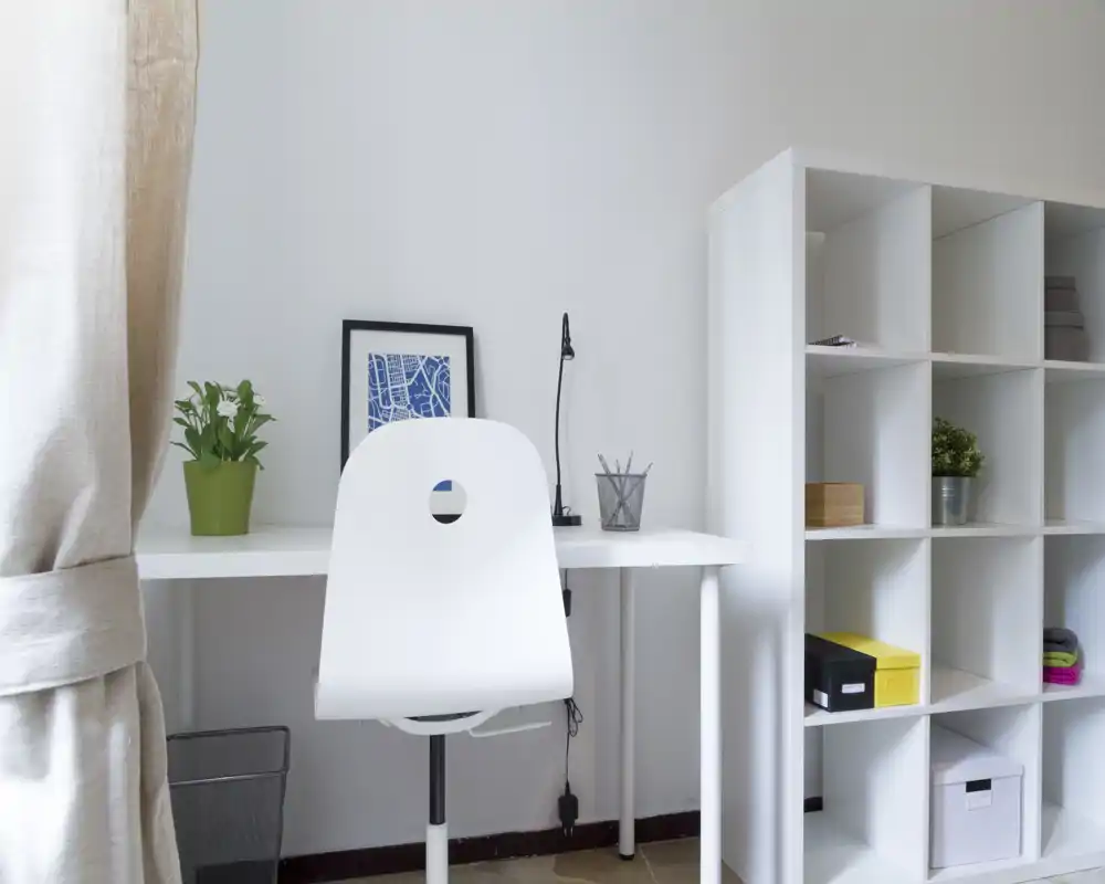 Bright, minimalist workspace with a white desk, shelving unit and a simple chair — ideal for a compact home office or study corner.