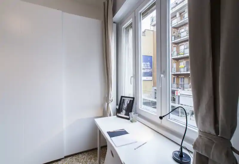 Coin chambre compact avec armoire blanche et bureau côté fenêtre, lumière naturelle abondante — adapté pour une personne ou un espace de travail dans la chambre.