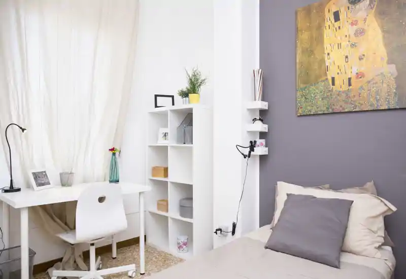 Camera singola luminosa e ben arredata con letto confortevole, scrivania vicino alla finestra e decorazioni murali eleganti — ideale per studenti o un professionista single.