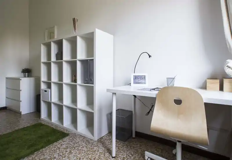 Espace de vie lumineux et minimaliste avec une étagère blanche et un bureau bien rangé, parfait pour un coin bureau à domicile.