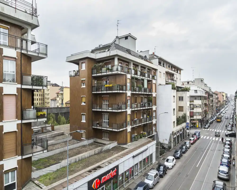 Veduta urbana con palazzi residenziali, balconi, auto parcheggiate e linea tranviaria — perfetta per valorizzare il quartiere e i servizi vicini.