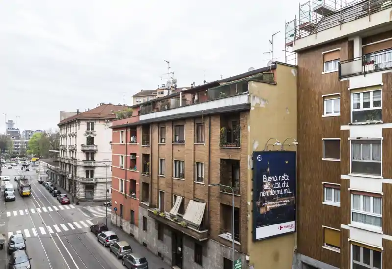 City street view showing apartment façades, parked cars and a tram line — ideal for showcasing urban location and nearby transport.