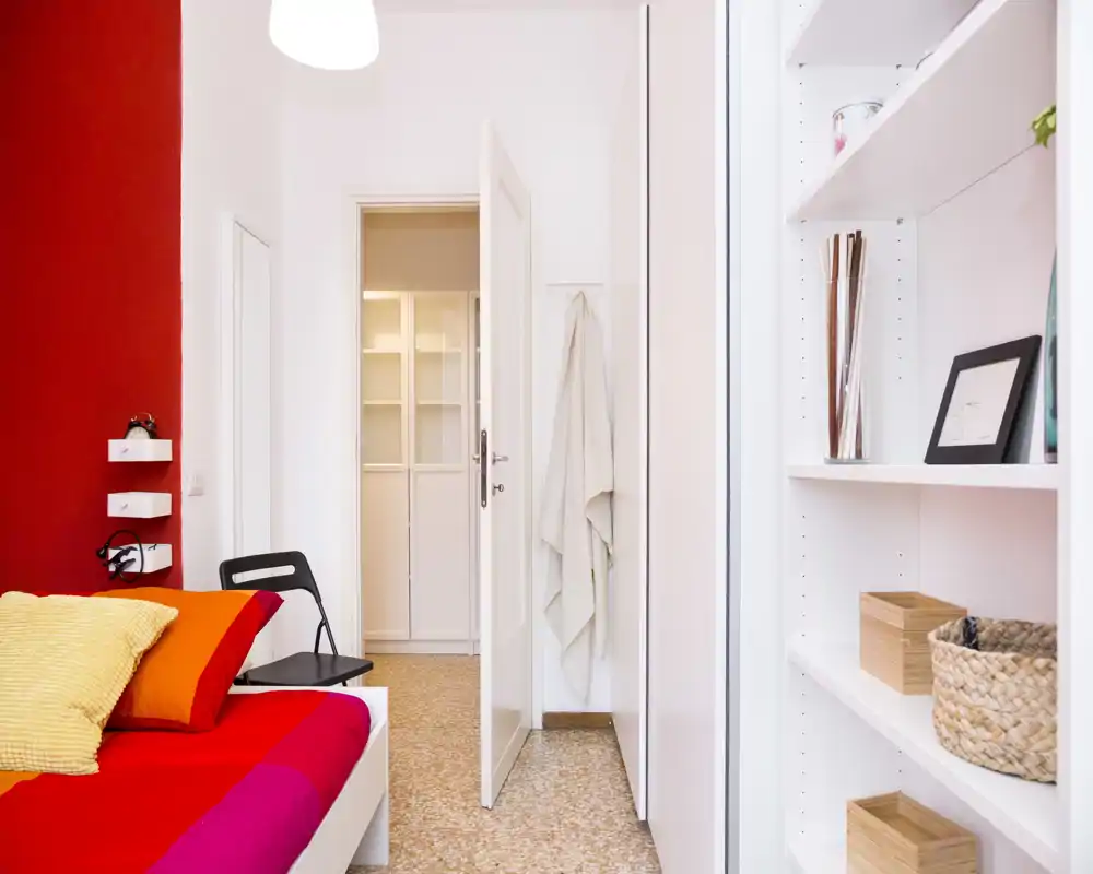 Bright, modern bedroom with a colorful bed and soft pillows; built-in shelving and tidy decor create a fresh, welcoming atmosphere perfect for short-term rentals.