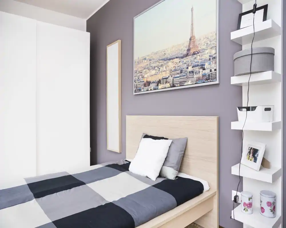 Bright, modern bedroom with a wooden bedframe, patterned bedding and tasteful wall art above the headboard, offering a clean and inviting sleeping space.