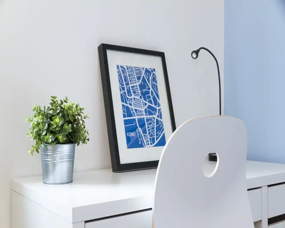 Angolo scrivania luminoso e minimale con sedia bianca, stampa blu incorniciata e una pianta in vaso: un elegante spazio di lavoro o angolo studio.