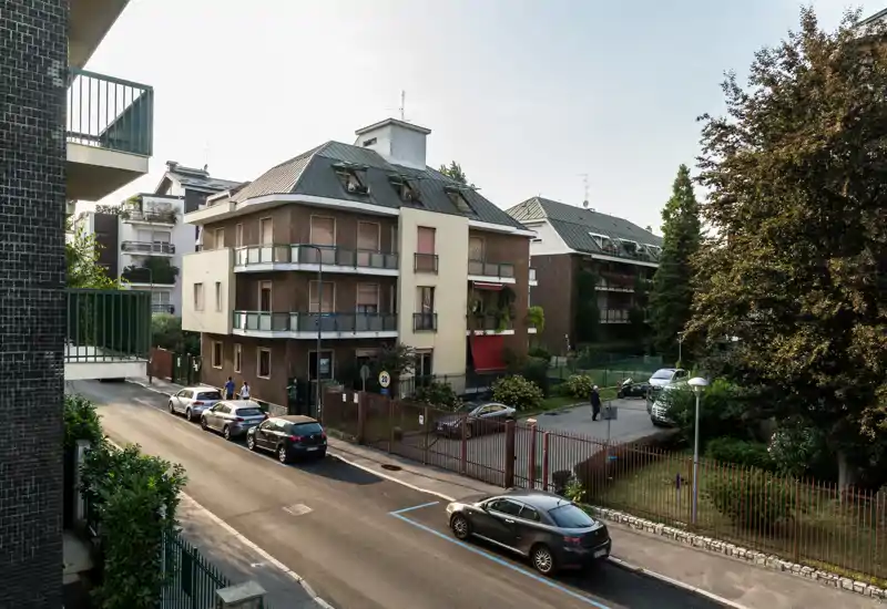 Vista stradale di un edificio residenziale con auto parcheggiate, utile per mostrare l'esterno e l'intorno della proprietà.
