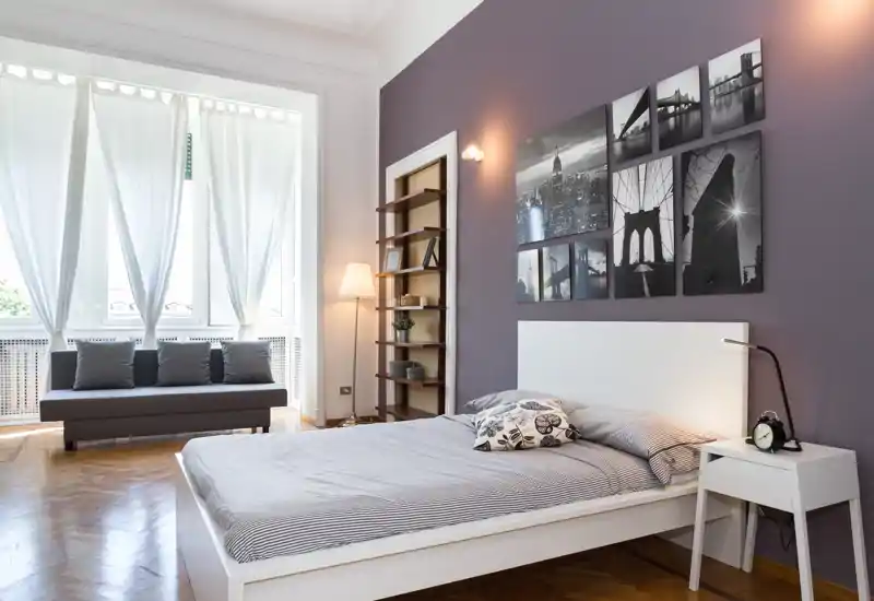 Dormitorio amplio y con estilo, con cama blanca, textiles acogedores y grandes ventanas que dejan entrar mucha luz natural.