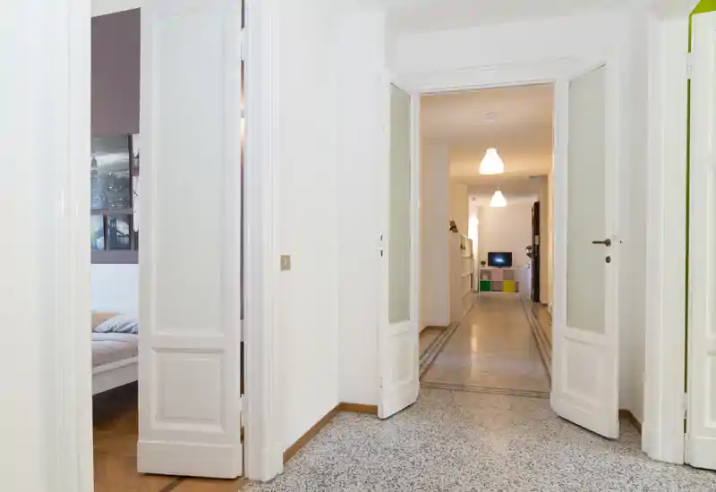 Bright entrance hallway with double doors opening onto a long corridor; tiled floor and clean white walls create an airy first impression.
