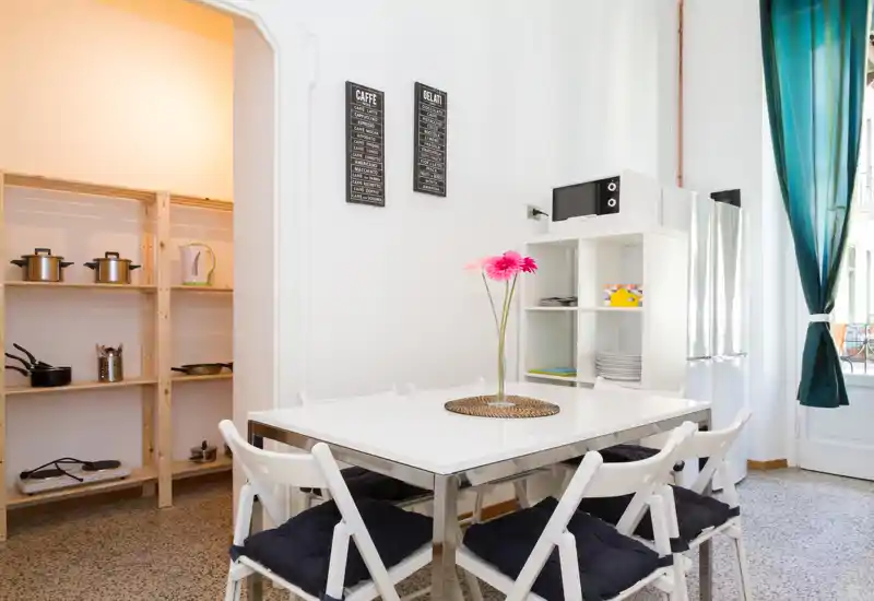 Bright, modern dining area with a white table set for six, cushioned folding chairs and a decorative vase—ideal for casual meals in a compact, airy space.