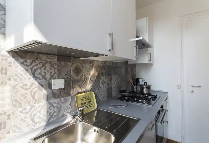 Compact modern kitchen with patterned tile backsplash, stainless sink and a gas hob. Bright, well-organized space ideal for short-term rentals.
