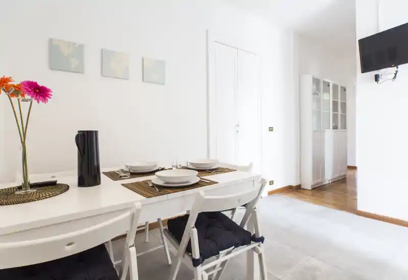 Bright, modern dining area with a set table, white chairs and simple decoration — comfortable space for casual meals.