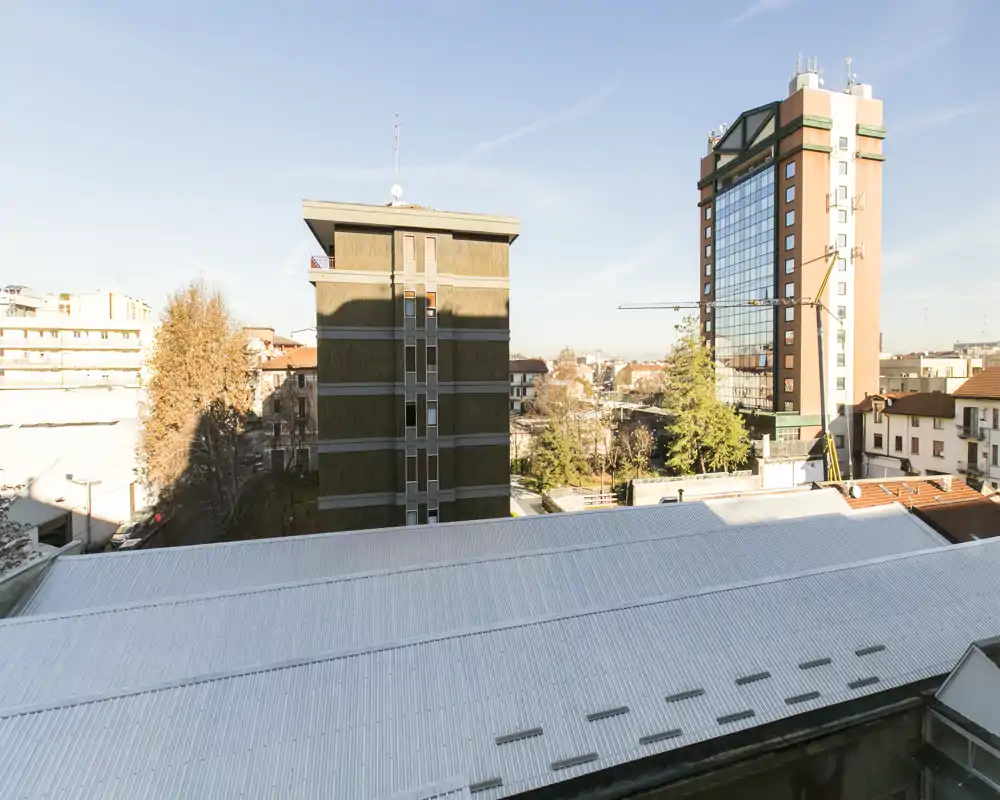 Vista cittadina luminosa con edifici vicini e un grande tetto visibile in pieno giorno — ottima per mettere in evidenza l’affaccio esterno dell’appartamento.