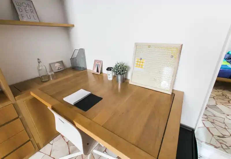Accogliente angolo scrivania con piano in legno, oggetti decorativi e una piccola pianta — perfetto per lavoro da remoto o studio.