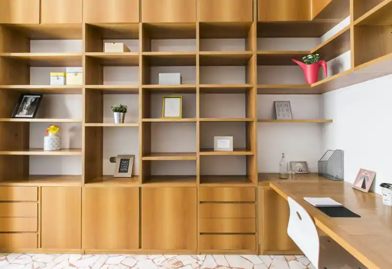 Area studio luminosa e moderna con scaffalature in legno a tutta parete e scrivania integrata — perfetta come ufficio domestico o spazio espositivo.