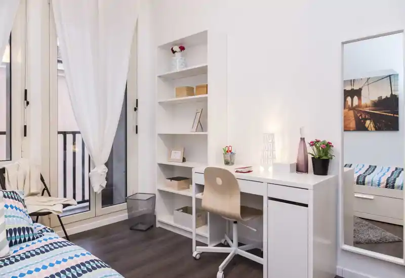 Chambre lumineuse et moderne avec lit à motifs, bureau et étagères; grande fenêtre apportant une belle lumière naturelle et un coin travail chaleureux.