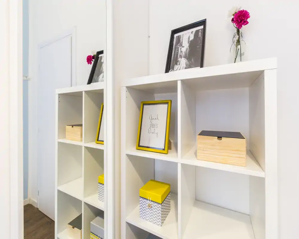 Bright, minimal entrance area with a white cubed shelving unit, decorative boxes and framed pictures—clean, welcoming hallway storage.