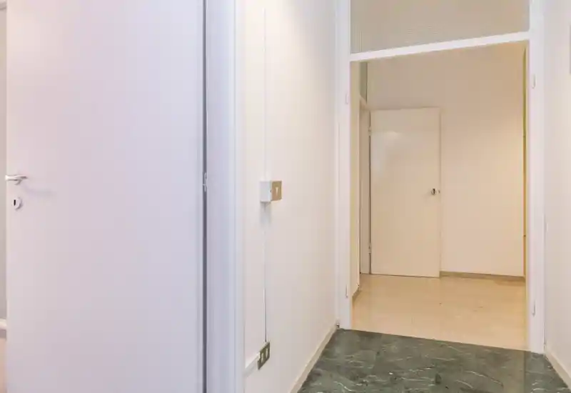 Bright, minimal entrance/hallway with clean white walls and polished floors; simple layout suitable for an apartment entry or corridor.