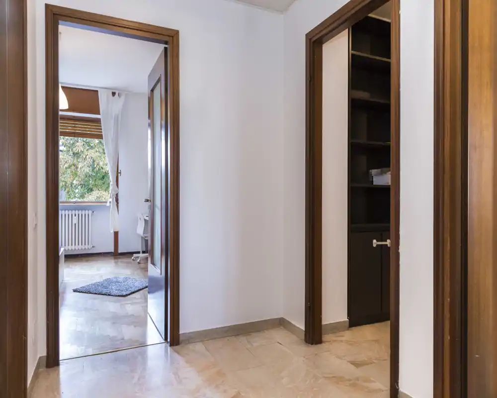 Simple, bright entrance/hallway with marble floor, white walls and wooden door frames leading to adjacent rooms.