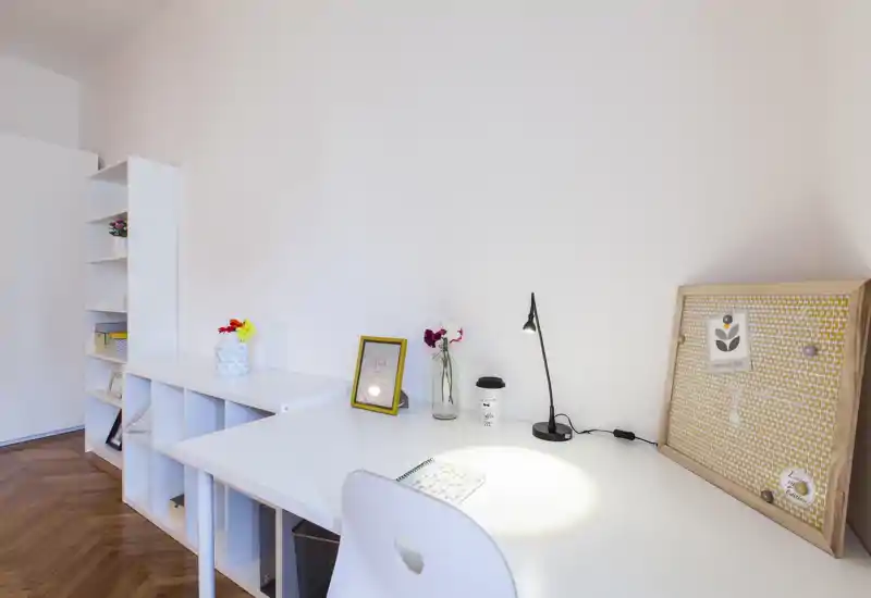 Coin lumineux et minimaliste avec bureau blanc, étagères, lampe de bureau et petits objets décoratifs — un espace adapté pour un coin bureau ou d'étude compact.
