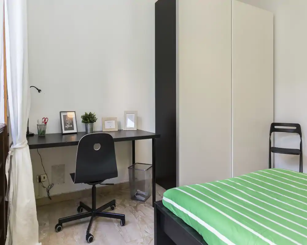 Dormitorio moderno y luminoso con cama arreglada, escritorio y armario — ideal para estudiante o profesional. La luz natural y las líneas limpias dan una sensación fresca y ordenada.