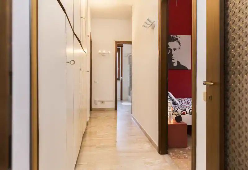 A bright, well-lit hallway with built-in storage leading to adjacent rooms; polished floor and warm wall lighting create an inviting entrance corridor.