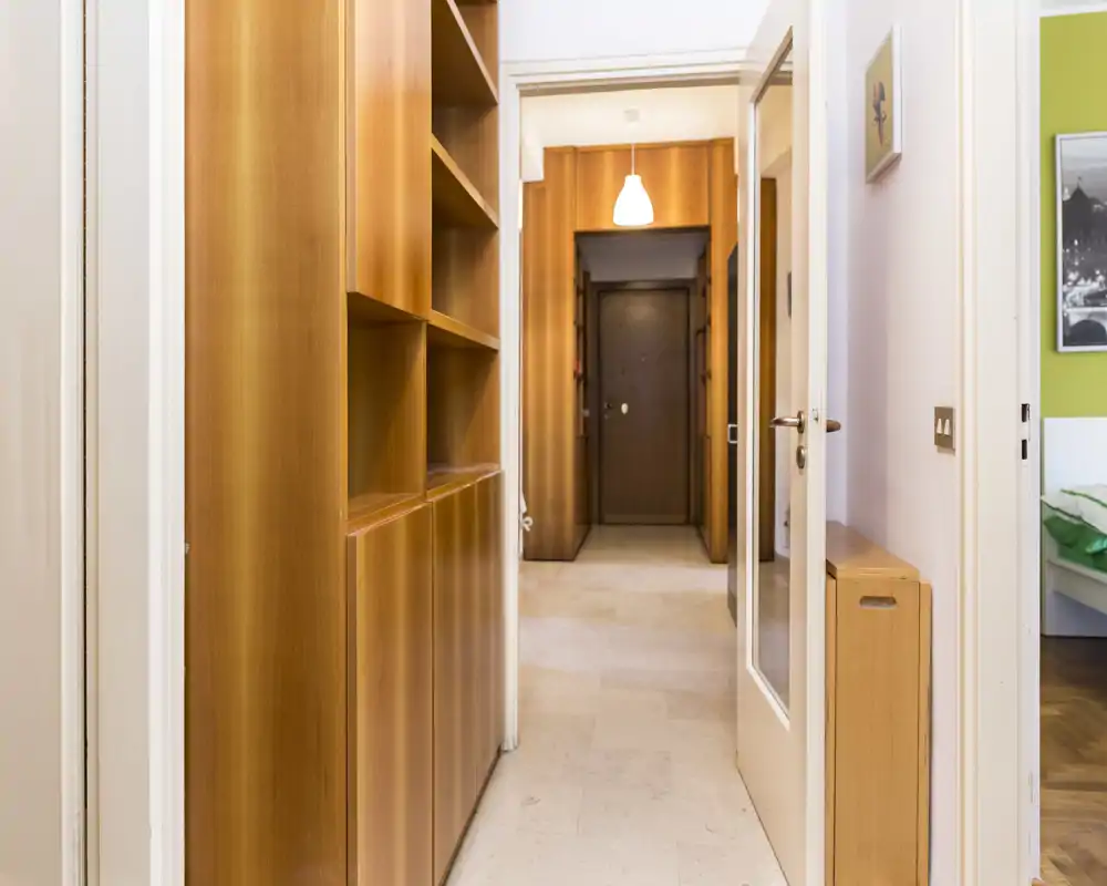 Vestíbulo interior luminoso con armarios de madera empotrados y puerta principal visible; suelo de baldosas e iluminación neutra, adecuado para mostrar la entrada en el anuncio.