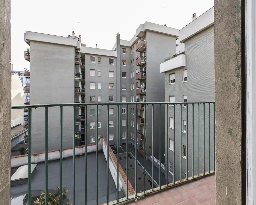 Balcone con vista sul cortile interno e sugli edifici adiacenti; pavimento piastrellato e ringhiera metallica in primo piano, ideale come piccolo spazio esterno privato.