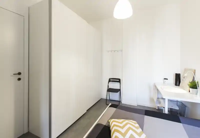 Bright, minimal bedroom with a visible double bed, built-in wardrobe and a small desk — clean, modern styling suitable for rental photos.