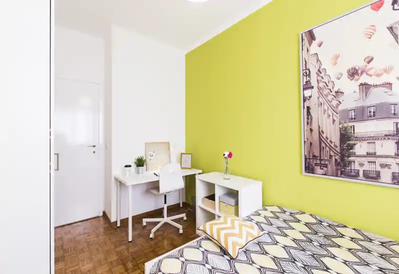 Bright, modern single bedroom with patterned bedding, a study desk and cheerful lime-green accent wall — ideal for students or short stays.