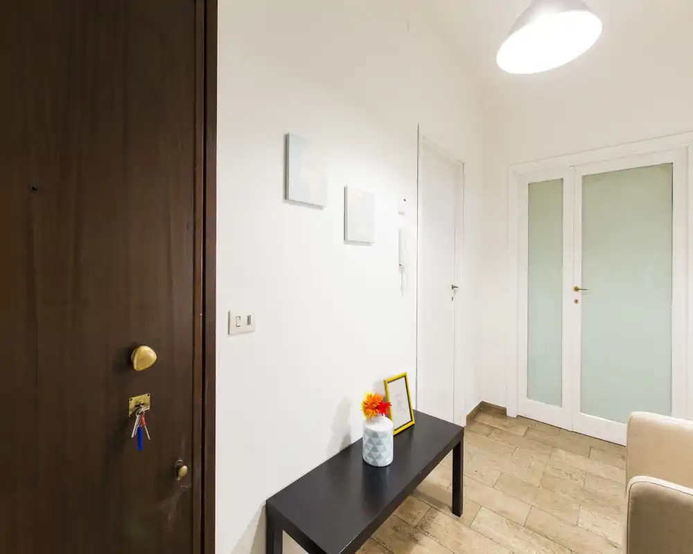 Bright and tidy entry hallway with a bench, decorative vase and wall hooks; suitable photo to show the apartment entrance area.