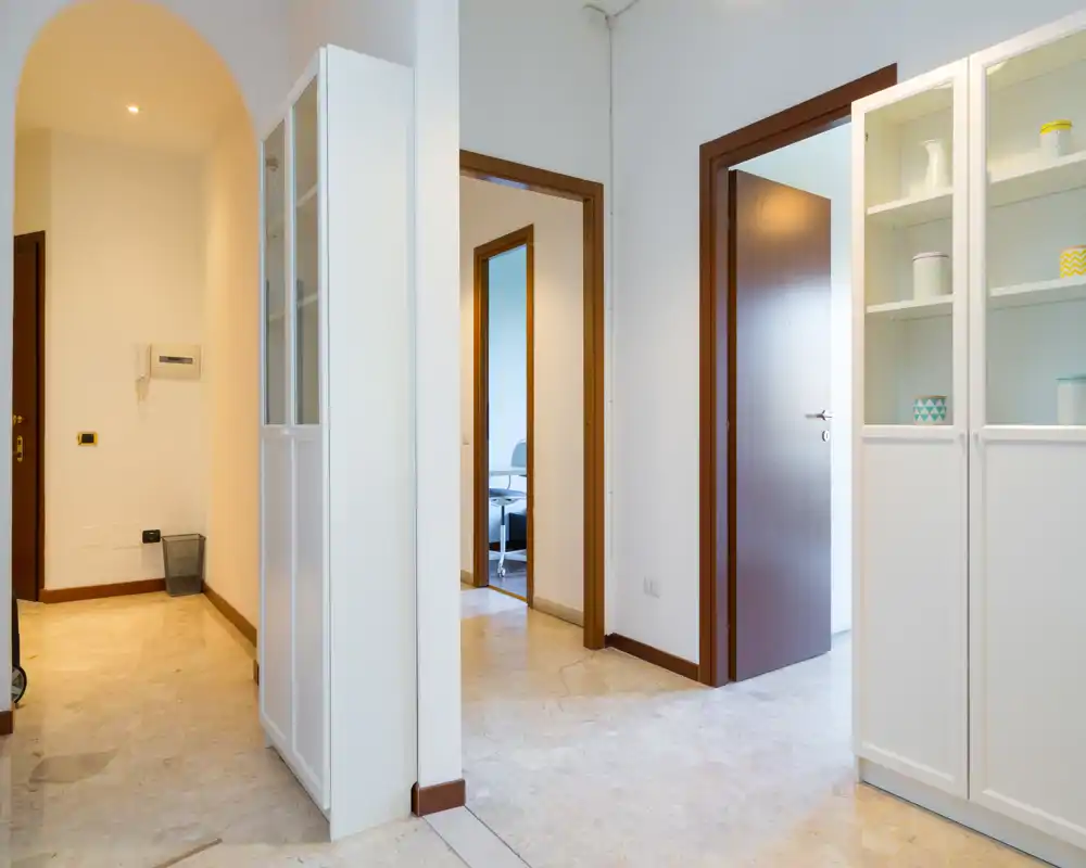 Entrada luminosa y limpia con suelo de mármol, paredes blancas y armarios empotrados — un espacio de paso acogedor que conecta varias habitaciones.