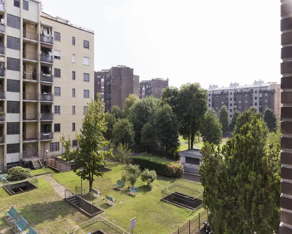 Communal courtyard with green lawns, benches and trees; low-rise apartment blocks surround the garden, offering a peaceful outdoor area.
