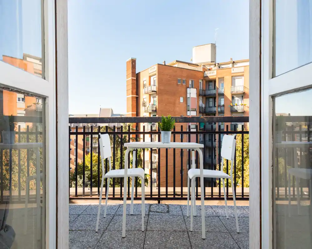 Balcón soleado con una pequeña mesa y dos sillas, ideal para el café de la mañana y las vistas a la ciudad.