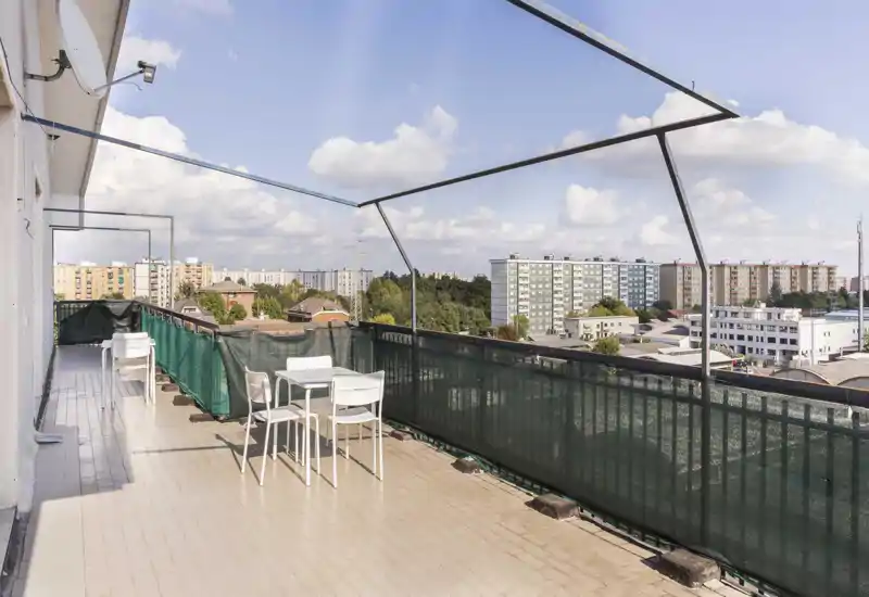 Spacious sunlit balcony with seating and panoramic city views — ideal for relaxing or outdoor dining under open sky.