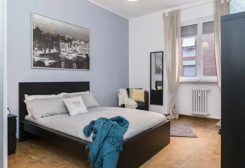 Camera da letto luminosa e ben allestita con letto matrimoniale, tessili morbidi e luce naturale — perfetta per foto di affitto.