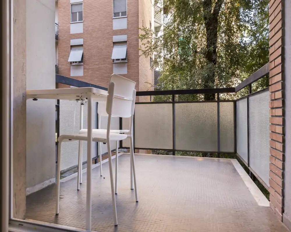 Balcone soleggiato con un piccolo tavolo e due sedie, ideale per il caffè mattutino e la vista sulla città.