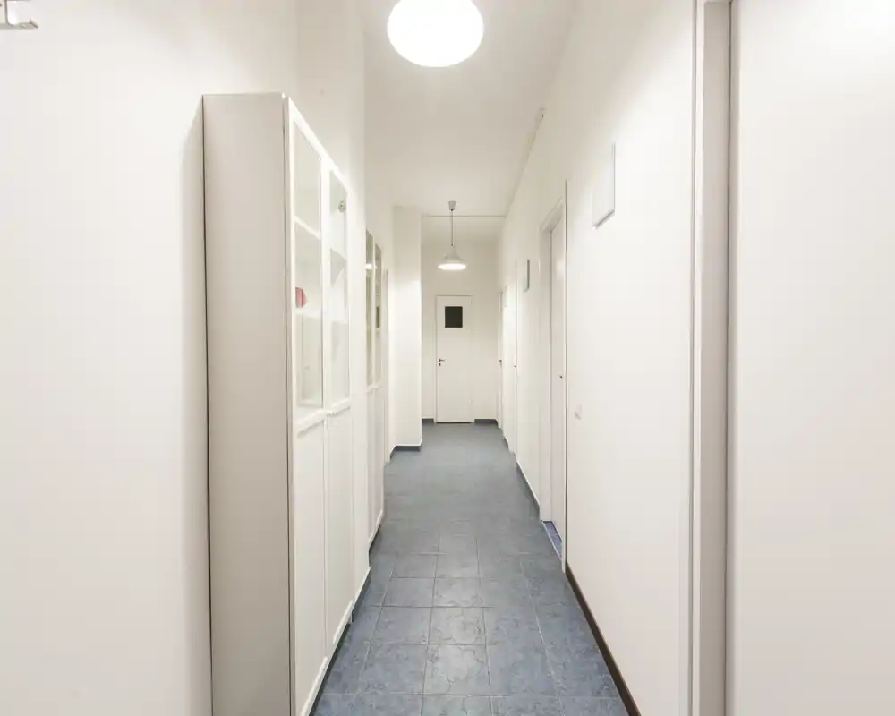 Pasillo de entrada luminoso y minimalista con suelo de baldosas, paredes blancas y armarios empotrados: limpio y bien iluminado, apto para un anuncio de alquiler.