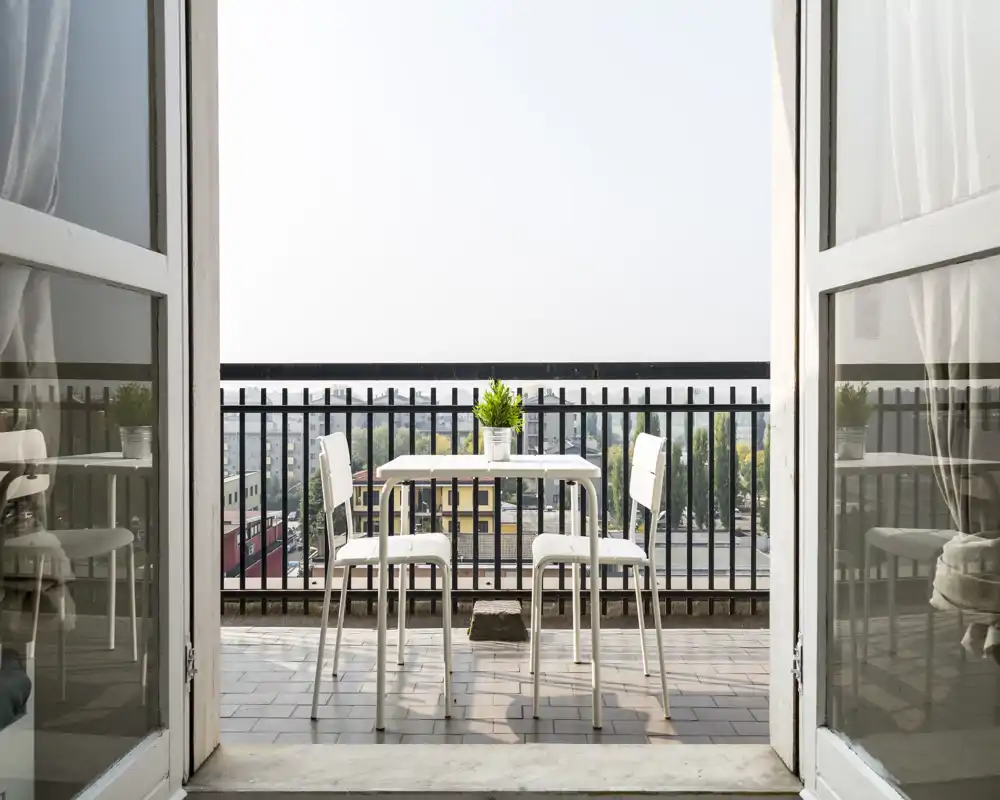 Balcone soleggiato con un piccolo tavolo e quattro sedie che si affaccia sulla città — ideale per colazioni o pasti leggeri con una bella vista urbana.