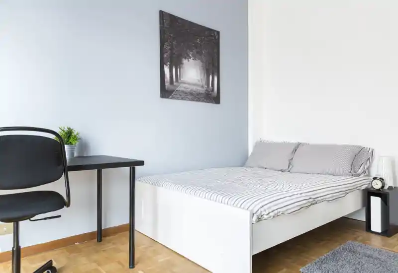 Dormitorio luminoso y minimalista con cama doble, mesita de noche y un pequeño escritorio — estilo moderno y limpio, ideal para un anuncio.