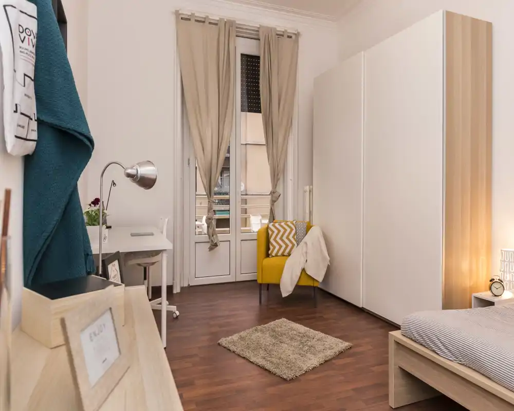 Bright, well-styled bedroom with a comfortable bed, wooden flooring, a cozy armchair and large wardrobe — ideal for a single or couple. Natural light and warm accents create an inviting atmosphere.