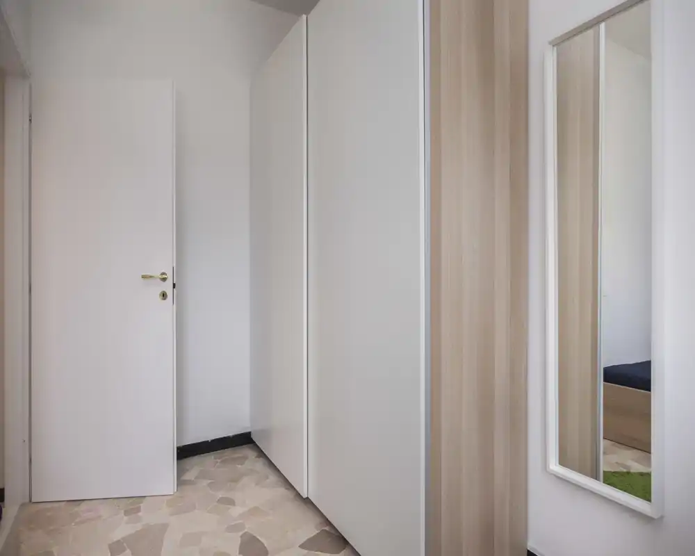 Compact entrance or hallway with built-in wardrobes, a full-length mirror and neutral finishes — practical storage and a clean, minimalist look.