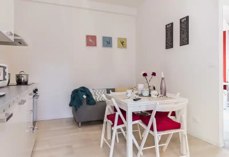 Bright, compact living area with a small dining table, cozy sofa and decorative accents — ideal for a city apartment.