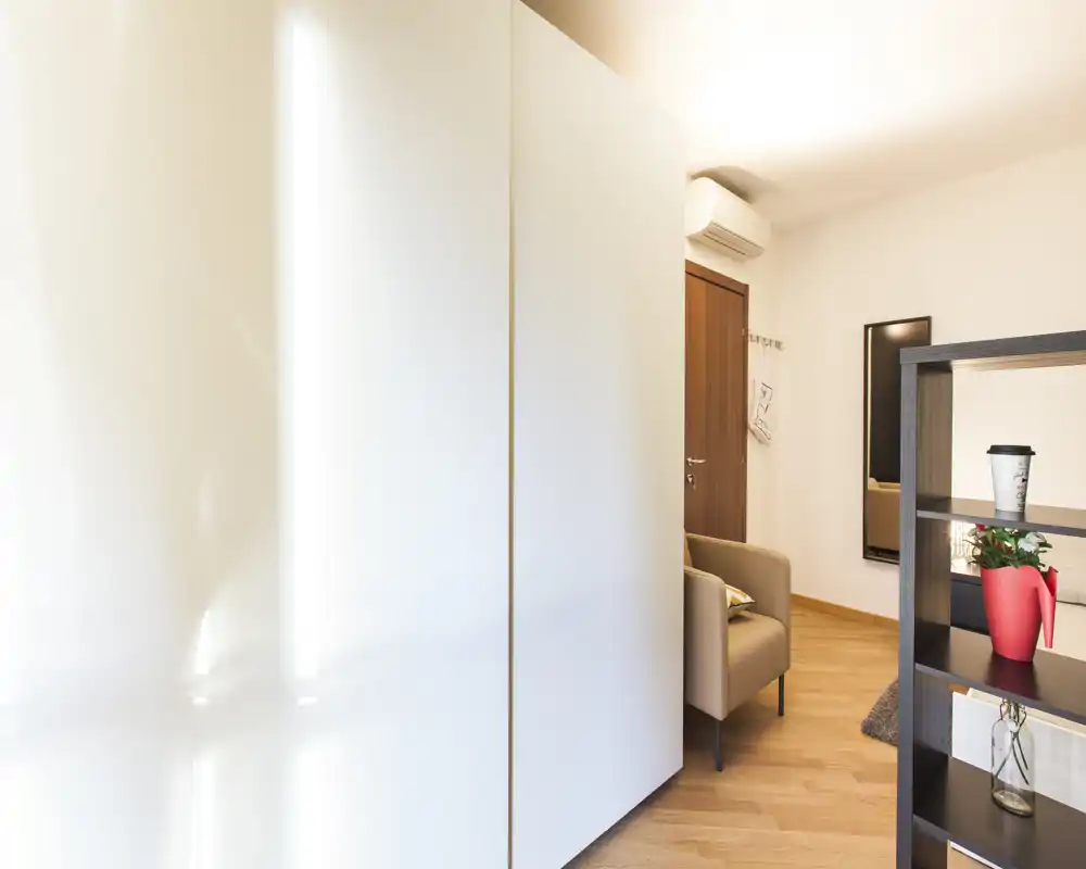 Angolo soggiorno moderno e luminoso con poltrona, libreria a giorno e pavimento in legno caldo — un angolo accogliente per rilassarsi.