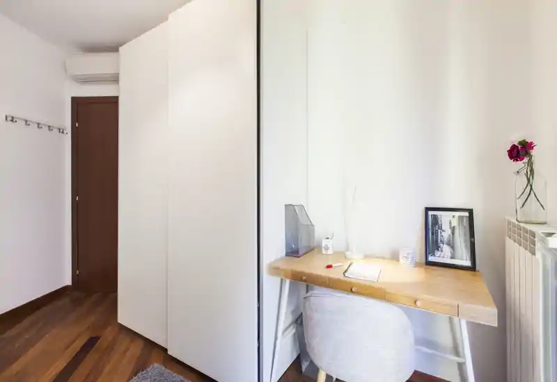 Rincón de dormitorio con armario empotrado y un escritorio de madera sencillo, luminoso y de estilo minimalista — ideal para estudio o habitación de invitados.