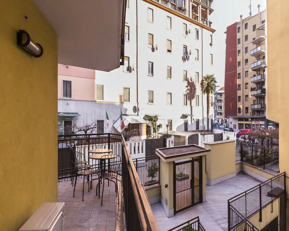 Terrazza privata soleggiata con tavolo e sedie che si affaccia su un cortile urbano tranquillo — ideale per caffè mattutino o relax all'aperto.