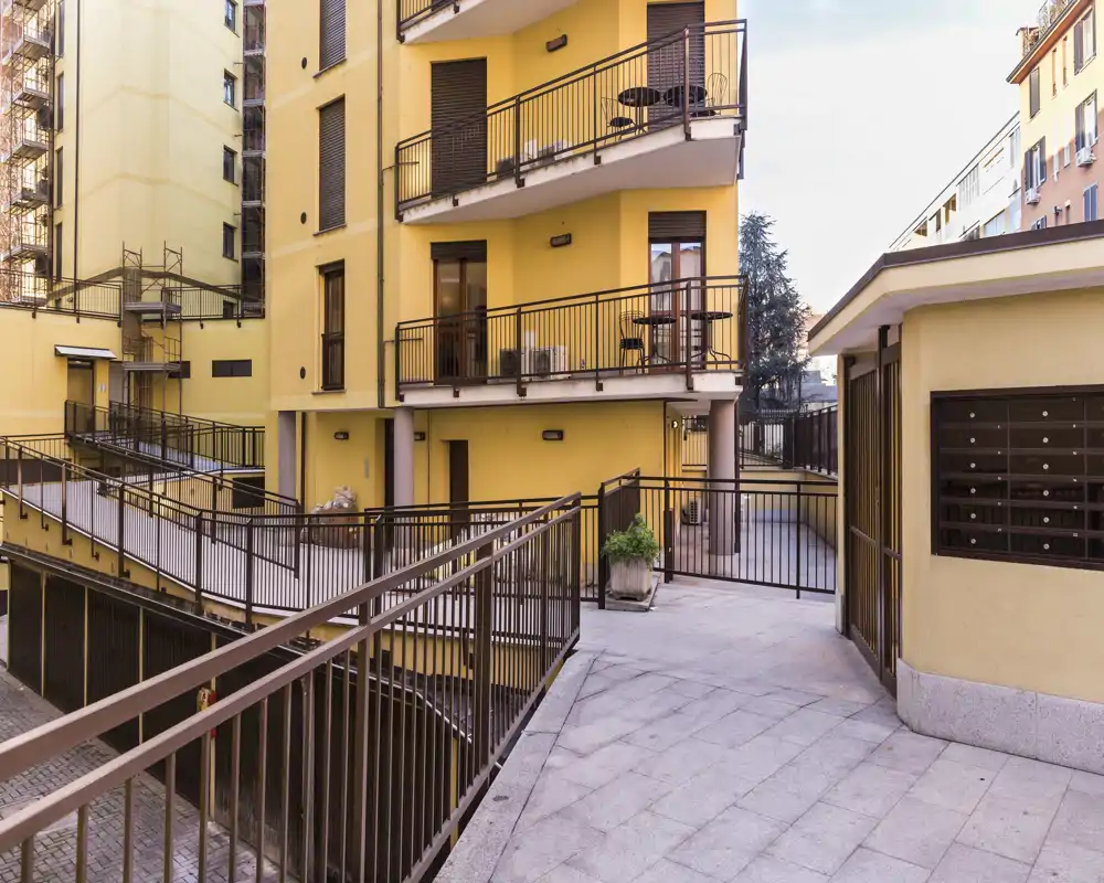 Cortile condominiale luminoso con rampe di accesso e vista sui balconi — area esterna ben illuminata ideale per ingresso e circolazione.