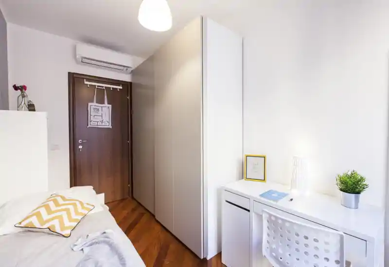 Bright modern bedroom with a single bed, large wardrobe and a neat white desk. Clean lines, warm wooden floor and cozy textiles make it ideal for a comfortable stay.