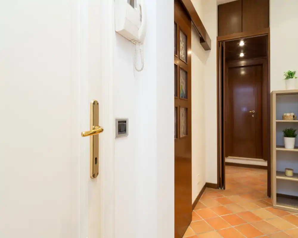 Ingresso luminoso e ordinato con pavimento in cotto, porte in legno e una piccola libreria a vista — uno spazio d'ingresso funzionale e accogliente.