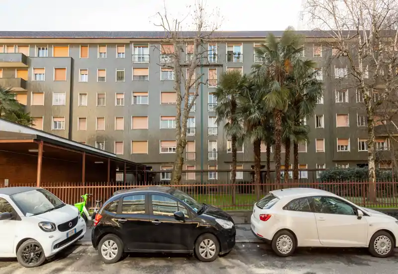 Exterior street view of a residential building façade with parked cars and palm trees in front, suitable for showcasing location and street-facing condition.